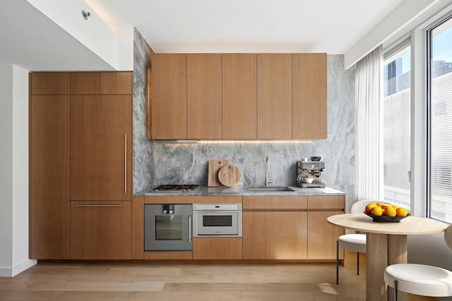 kitchen featuring appliances with stainless steel finishes, a sink, light wood-style floors, and modern cabinets