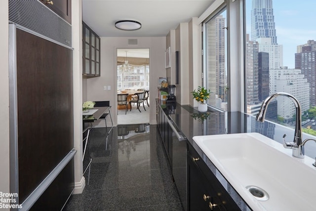 kitchen with a sink, granite floors, built in fridge, a view of city, and glass insert cabinets