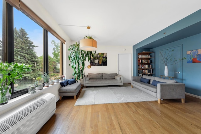 living area featuring light wood-type flooring and an AC wall unit