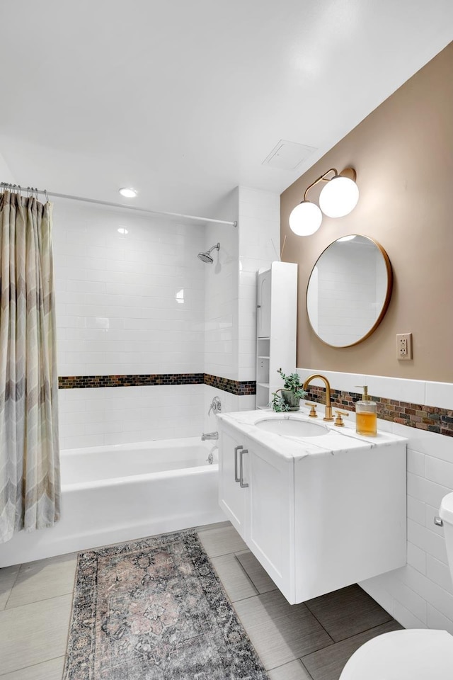 bathroom with shower / bath combo, toilet, tile walls, tile patterned floors, and vanity