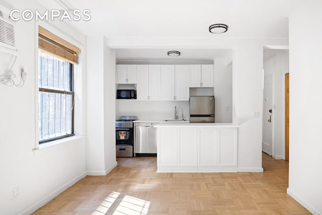 226-230 E 12th St Unit 1H, New York City, NY 10003 - kitchen featuring stainless steel appliances, a sink, white cabinets, light countertops, and baseboards