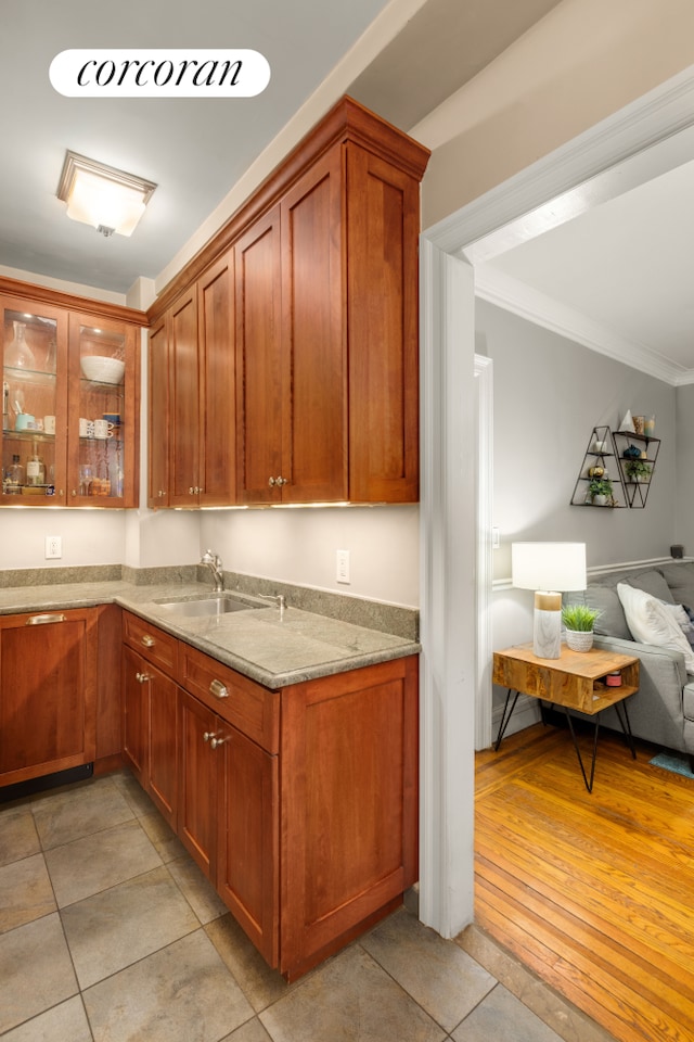 kitchen featuring a sink, open floor plan, light stone countertops, glass insert cabinets, and light tile patterned flooring