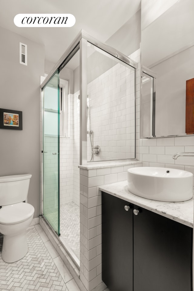 bathroom with a shower stall, toilet, and vanity