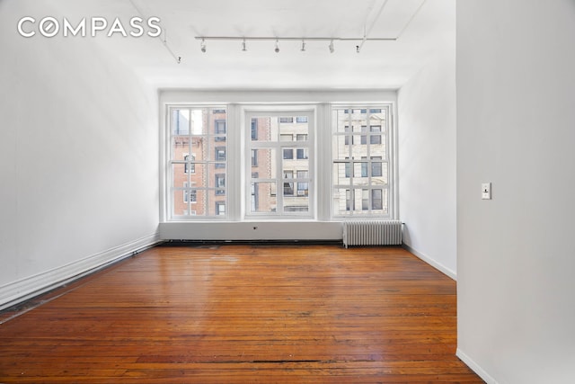 16 E 17th St Unit 3, New York City, NY 10003 - unfurnished room featuring radiator heating unit, rail lighting, hardwood / wood-style floors, and baseboards