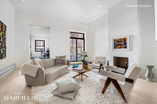 living area featuring wood finished floors, recessed lighting, a baseboard heating unit, and baseboards