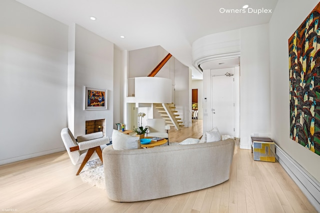living area featuring a baseboard heating unit, light wood-type flooring, stairway, and recessed lighting