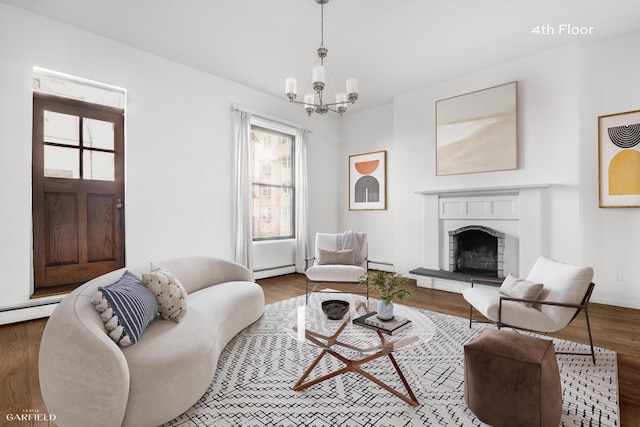 living area with healthy amount of natural light, a chandelier, a baseboard radiator, and a fireplace with raised hearth