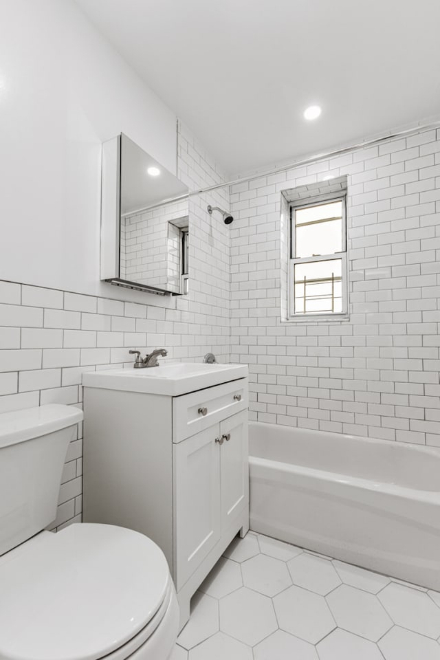 full bath featuring tile walls, toilet, tub / shower combination, vanity, and tile patterned floors
