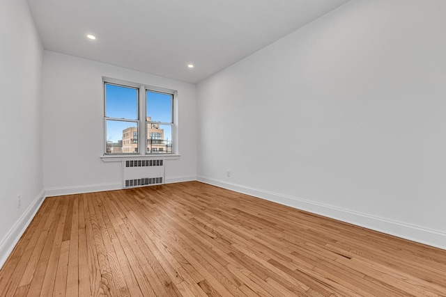 unfurnished room featuring radiator, light wood finished floors, baseboards, and recessed lighting