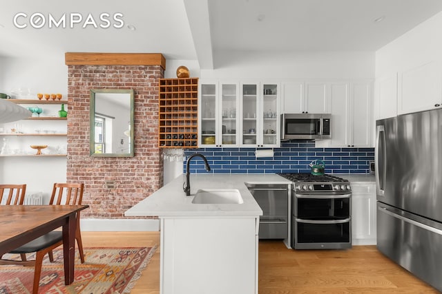 kitchen featuring appliances with stainless steel finishes, a sink, light wood-style floors, and white cabinetry