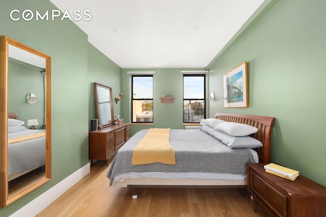 bedroom with wood finished floors, vaulted ceiling, and baseboards
