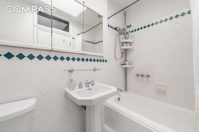 full bath featuring tile walls, toilet, and shower / bathtub combination with curtain