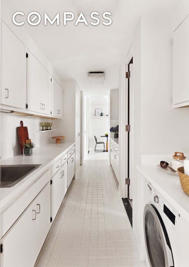 washroom with washer / dryer, light tile patterned floors, and cabinet space