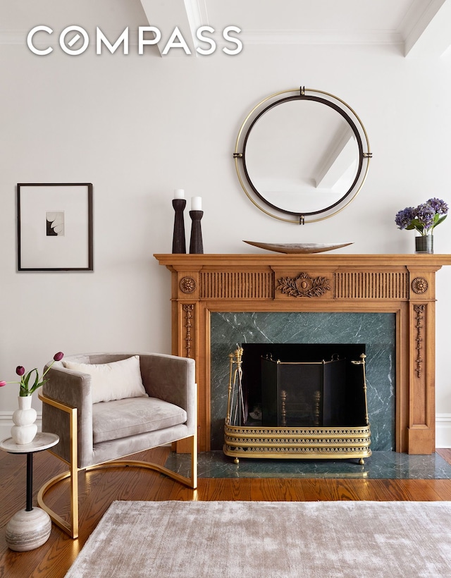 living area with a high end fireplace, ornamental molding, and wood finished floors