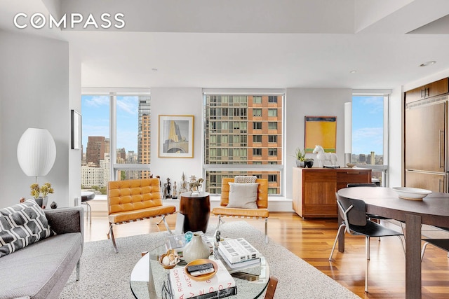 living room featuring a skyline view, wood finished floors, plenty of natural light, expansive windows, and recessed lighting