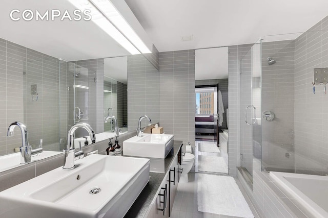 full bathroom featuring tile walls, a shower stall, tile patterned floors, and vanity