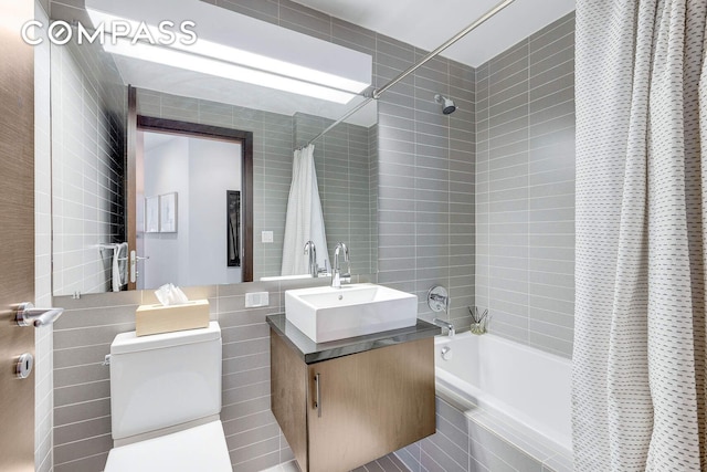 full bath with tile walls, tiled shower / bath, vanity, and toilet
