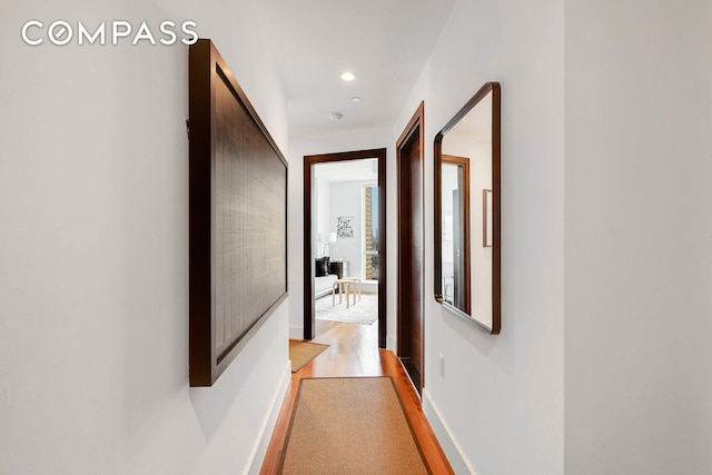 hallway featuring recessed lighting, light wood-type flooring, and baseboards