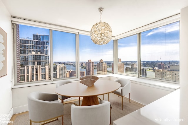 dining room featuring a city view, wood finished floors, baseboards, and a chandelier