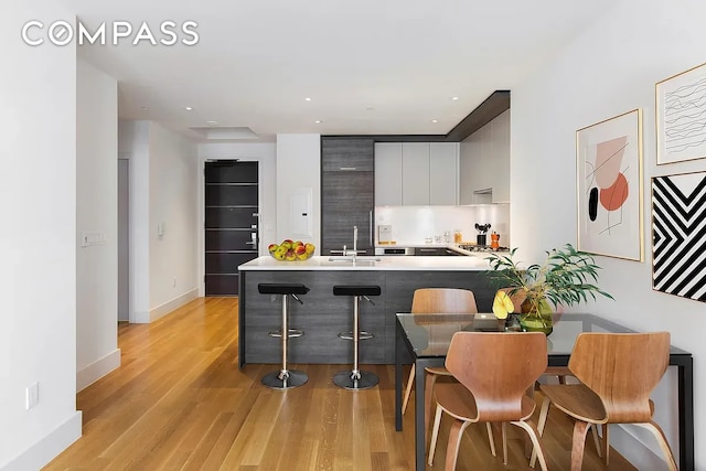 101 Leonard St Unit 4A, New York City, NY 10013 - kitchen with modern cabinets, light wood-type flooring, a peninsula, a kitchen bar, and a sink