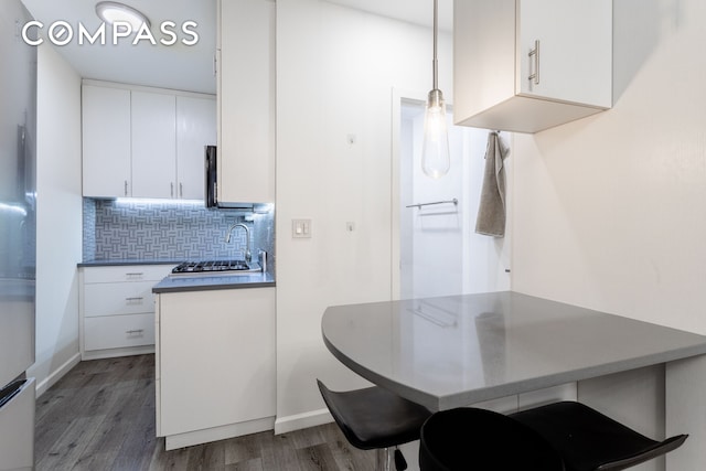 kitchen featuring wood finished floors, white cabinets, tasteful backsplash, and baseboards