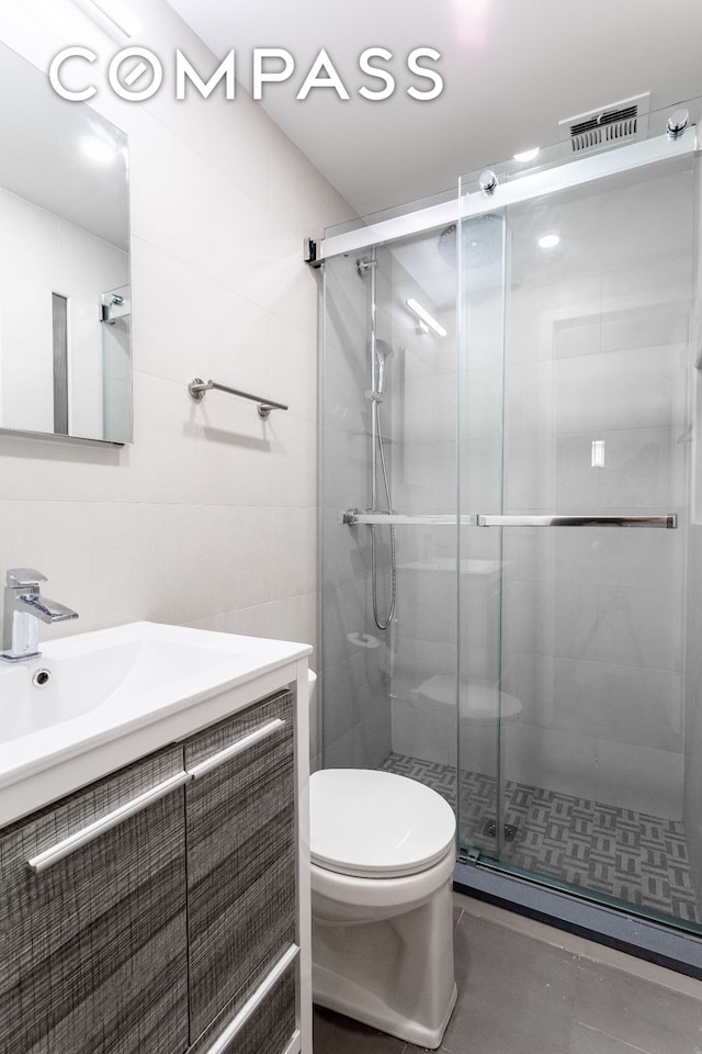 full bathroom featuring a shower stall, tile walls, toilet, vanity, and tile patterned flooring