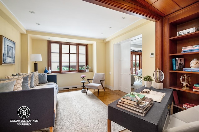 sitting room featuring healthy amount of natural light, wood finished floors, baseboards, and built in features