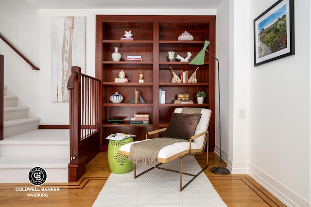sitting room with wood finished floors, stairs, and baseboards