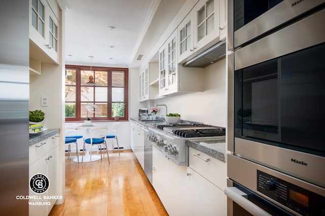 350 E 72nd St Unit 1A/2A, New York City, NY 10021 - kitchen featuring stainless steel gas cooktop, white cabinets, a sink, dark countertops, and ornamental molding