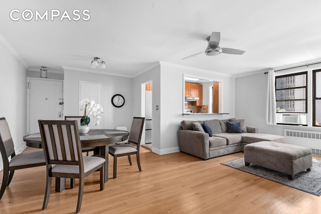 living room featuring radiator heating unit, ceiling fan, light wood-style flooring, crown molding, and baseboards