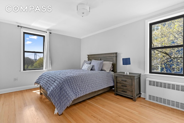 bedroom featuring radiator, baseboards, light wood-style flooring, crown molding, and multiple windows