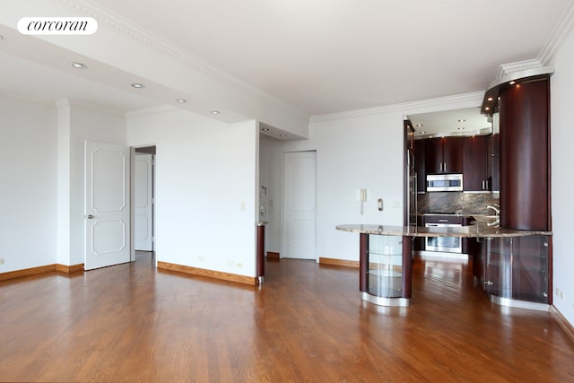 kitchen with stainless steel microwave, dark wood-style floors, baseboards, a breakfast bar, and crown molding
