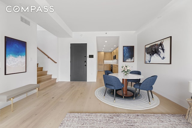 dining space with light wood-style flooring, stairs, baseboards, and recessed lighting