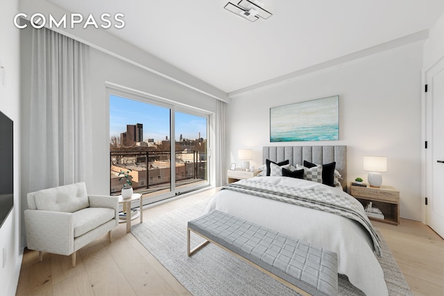 bedroom with light wood finished floors, access to outside, and a city view