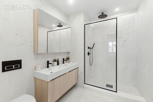 full bath with a marble finish shower, double vanity, recessed lighting, toilet, and tile walls