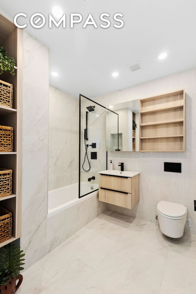full bath featuring  shower combination, toilet, marble finish floors, tile walls, and vanity