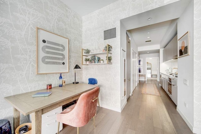 dining area with hardwood / wood-style flooring, a desk, wallpapered walls, and baseboards