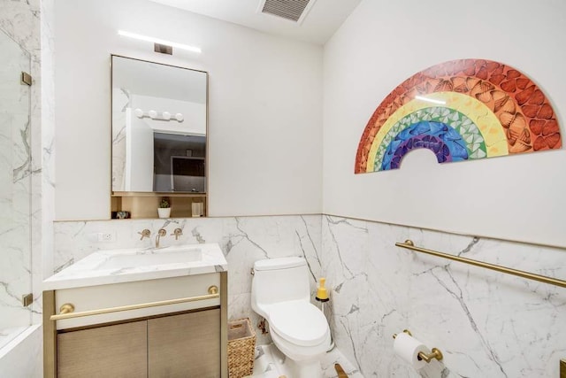 bathroom with vanity, toilet, tile walls, and a wainscoted wall