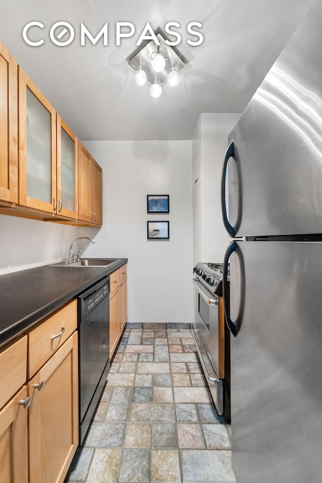 kitchen featuring appliances with stainless steel finishes, a sink, dark countertops, brick patterned flooring, and glass insert cabinets