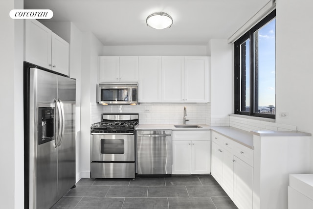 304 E 65th St Unit 26B, New York City, NY 10065 - kitchen with stainless steel appliances, a sink, tasteful backsplash, white cabinets, and light countertops