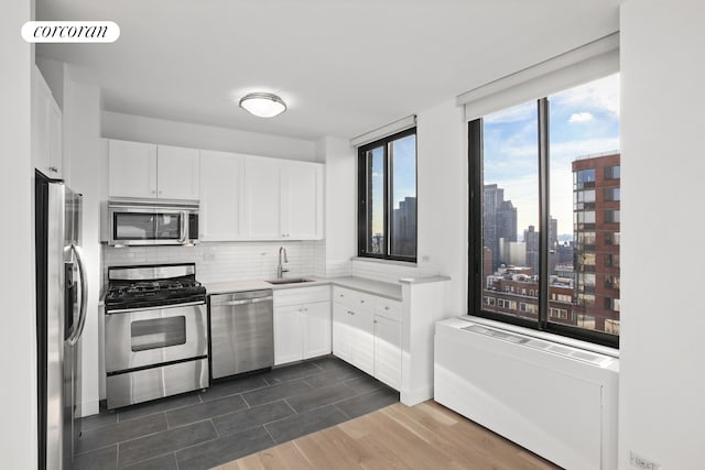 304 E 65th St Unit 26B, New York City, NY 10065 - kitchen with stainless steel appliances, a sink, backsplash, dark wood-style flooring, and light countertops