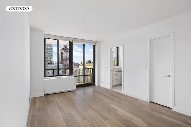 304 E 65th St Unit 26B, New York City, NY 10065 - spare room featuring wood finished floors, baseboards, and a city view