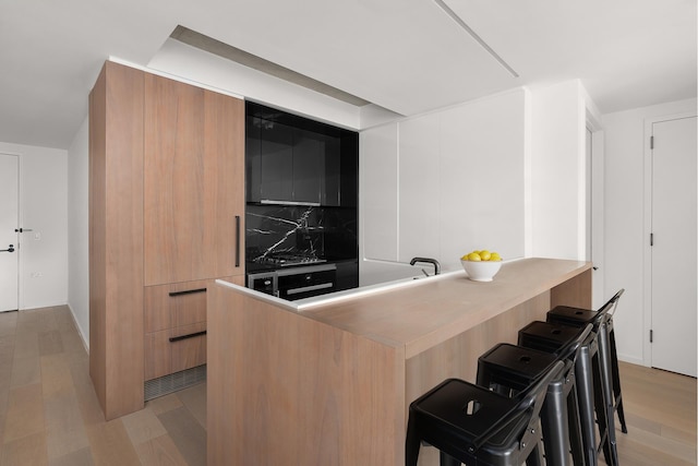 196 Orchard St Unit 7J, New York City, NY 10002 - bar area with light wood-style floors, tasteful backsplash, and baseboards