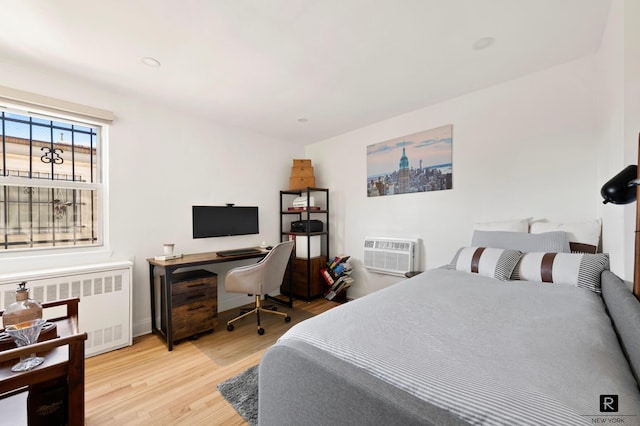 bedroom with radiator, a wall mounted air conditioner, wood finished floors, and baseboards