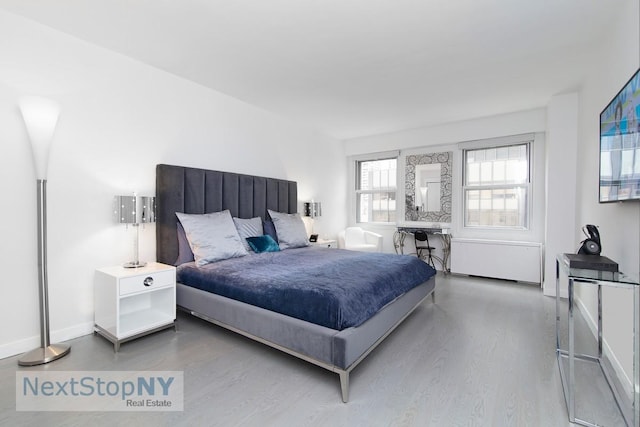 bedroom featuring wood finished floors and radiator