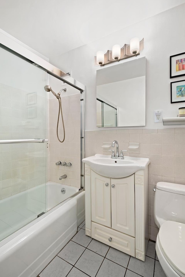 full bath featuring tile patterned floors, tile walls, toilet, enclosed tub / shower combo, and vanity