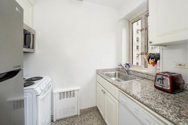 166 E 63rd St Unit 6B, New York City, NY 10021 - kitchen featuring stainless steel appliances, radiator, a sink, dark speckled floor, and white cabinets