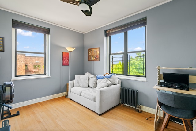 sitting room featuring radiator heating unit, crown molding, wood finished floors, ceiling fan, and baseboards