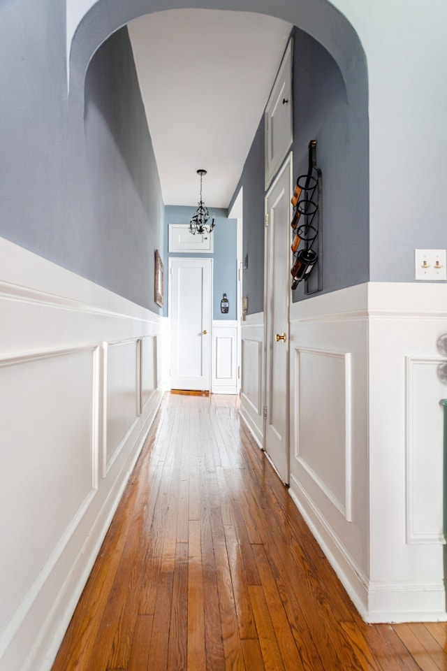175 E 93rd St Unit 3-B, New York City, NY 10128 - corridor with a decorative wall, hardwood / wood-style flooring, a wainscoted wall, a chandelier, and arched walkways