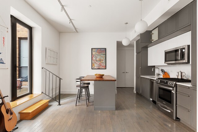 416 W 52nd St Unit 225, New York City, NY 10019 - kitchen featuring appliances with stainless steel finishes, wood-type flooring, rail lighting, backsplash, and a sink